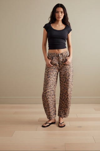A woman modeling wide-leg leopard-print pants with a black cropped t-shirt and black flip-flops, shown against a plain white background.