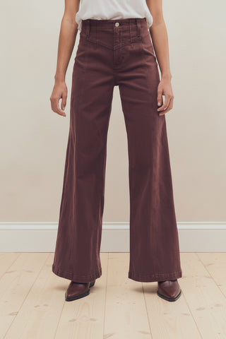 A person shown from the waist down wearing free people libre wide-leg brown corduroy pants and dark brown heeled shoes against a plain white studio background.