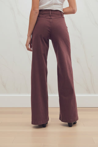 A person shown from the waist down wearing free people libre wide-leg brown corduroy pants and dark brown heeled shoes against a plain white studio background.
