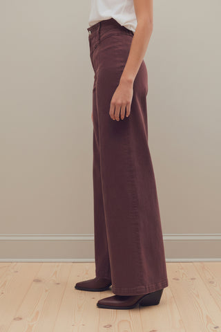 A person shown from the waist down wearing free people libre wide-leg brown corduroy pants and dark brown heeled shoes against a plain white studio background.