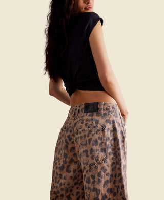 A model shown from the back wearing a black cropped t-shirt and high-waisted leopard-print wide-leg jeans. The photo is shot against a clean white background.